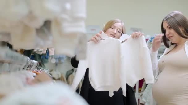 Δύο Νεαρές Γυναίκες Μητέρες Παιδικά Ρούχα Στο Μαγαζί Ενδιαφερόμενη Έγκυος — Αρχείο Βίντεο