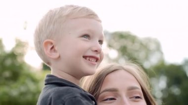 Mutlu bir aile. Park 'ta oğlu olan genç hamile bir anne. Aile birlikte zaman geçirir. Anne oğluna sarılıyor. Parkta aile gezisi.