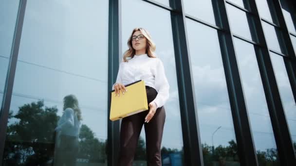 有工作证件的有魅力的女办公室经理 自信时尚的女商人在户外手握商业文件放松 漂亮的女士正对着玻璃楼摆姿势 — 图库视频影像