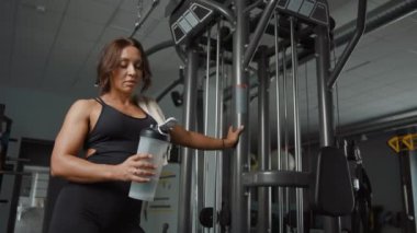 Spor kıyafetli yorgun bir kadının portresi spor salonunda spor şişesiyle.