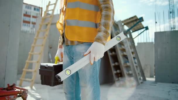 Bauarbeiter Mit Blasenfüllstandmessgerät Und Werkzeugkiste Steht Auf Baustelle — Stockvideo