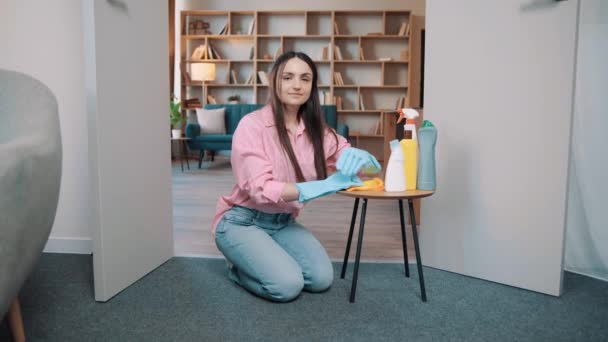 一个穿着粉色衬衫 戴着大大的橡胶手套的女孩坐在家里的地板上 摆出姿势拍照 房间里有洗涤剂的女人 — 图库视频影像
