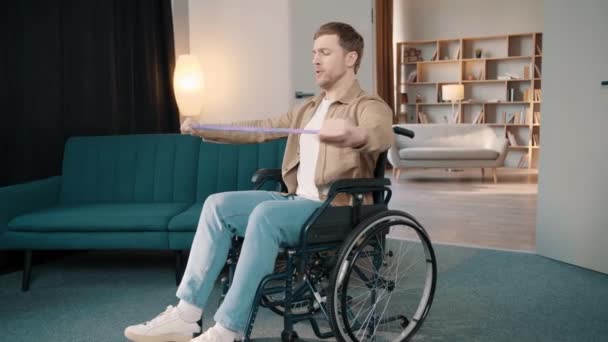 Mladý Běloch Sedí Invalidním Vozíku Natahuje Paže Gumičkou Doma — Stock video
