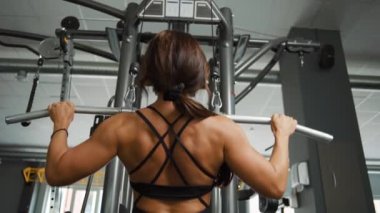 Spor salonunda kaslarını çalıştıran güzel, genç bir kadın.