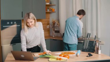 Mutfakta yemek yapan mutlu çift. Erkek, kırmızı biberi yıkıyor ve masada salata için bir kadına uzatıyor. mutfakta sağlıklı yiyecekler var.