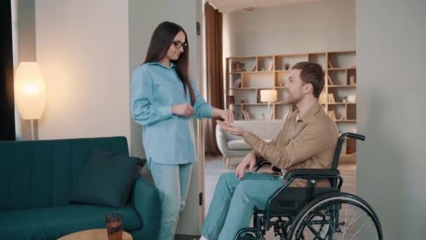 一位年轻女子和一位坐在轮椅上的残疾男子正在交谈 一位女性地产经纪人将钥匙交给了一位残疾男子 — 图库视频影像