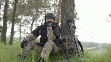 Mayın temizliği. Mayın detektörü ve sırt çantalı asker, ağır mayın temizliğinden sonra bir ağacın altında bitkin halde oturuyor.