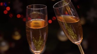 Mutlu çift şampanya kadehlerini tokuşturur ve yeni yılı birlikte kutlayalım. Parlak bir Noel ağacının önünde el ele tutuşalım.
