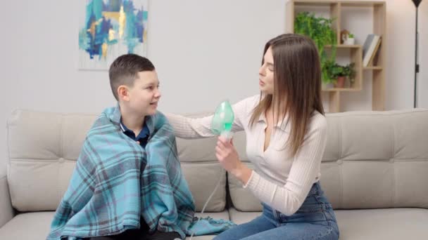 Matka Pomaga Choremu Synowi Używać Nebulizatora Podczas Objęcia Kanapie Domu — Wideo stockowe