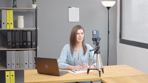 Gülümseyen Genç Bayan Blogcusu Kürsüde Cep Telefonunun Önünde Oturuyor Konuşuyor — Stok video