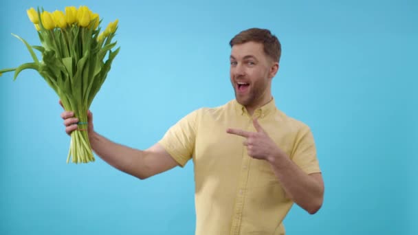 Człowiek Pokazując Kilka Żółtych Tulipanów Przed Niebieskim Tle — Wideo stockowe