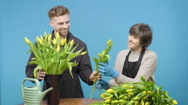 Mężczyzna Kobieta Organizując Żółte Kwiaty Niebieskim Tle — Wideo stockowe