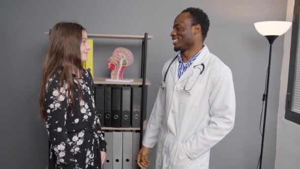 Médico Negro Abraza Paciente Joven Consultorio Médico Chica Muestra Corazón — Vídeos de Stock
