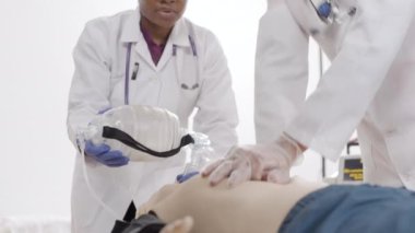 Oksijen maskeli mankene tıbbi profesyonel suni teneffüs uyguluyor. İlk yardım kursu