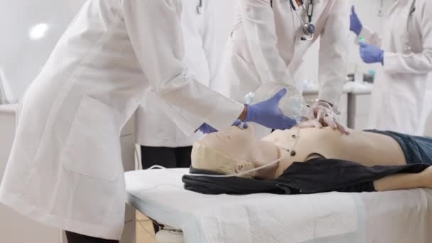 医疗诊所里穿着白色实验室外套和蓝色手套对假人进行急救的一组医生 — 图库视频影像