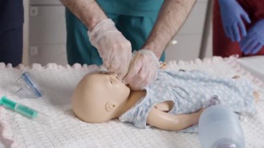 İlk yardım. Hastanede bebek mankeni muayene eden hemşire.