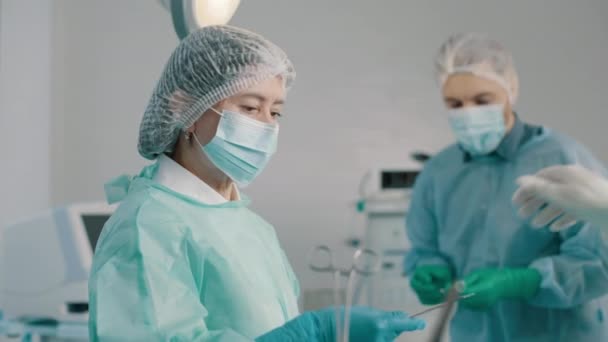 専門外科医のチームは手術室で麻酔の下で患者の手術を行います 看護師が医者に医療機器を手渡す — ストック動画