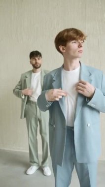 Yeni takım elbiseli iki adam duvarın önünde duruyor.