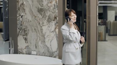 Döşeme salonu tasarımcısı telefonda müşteriyle proje tartışıyor