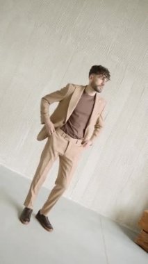 Bronz takım elbiseli adam duvara yaslanıyor.