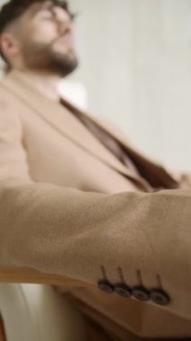 Yeni takım elbiseli adam sandalyede oturuyor.