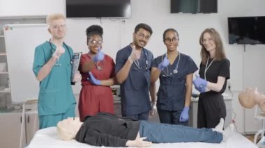Klinik ortamında ilk yardım teknikleri sergileyen bir grup tıbbi uzman. Başparmaklar yukarı.