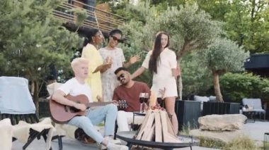Çeşitli arkadaşlar gitar müziğiyle yaz pikniğinin tadını çıkarıyorlar.