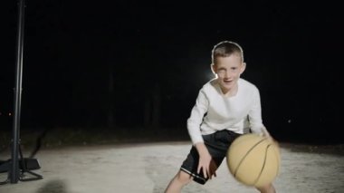 Yerel basketbol sahasında topu olan genç bir çocuk.