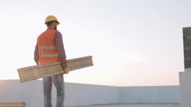 İnşaat işçisi gün batımında bölgede malzeme hazırlıyor, projeler inşa etmeye adanmış çabaları sergiliyor