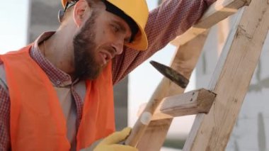 İnşaat işçisi gün batımında inşaat alanında merdiveni dikkatlice inceleyip hazırlıyor.