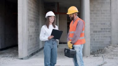 İnşaat işçileri inşaat alanında proje planlarını tartışırken planları analiz ediyor ve etkili takım çalışması için araçlar kullanıyorlar