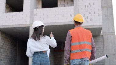 İnşaat işçisi inşaat alanında mühendisle işbirliği yapıyor ve proje planlarını tartışıyor