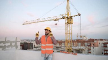 Şehir merkezinde gün batımında vinci olan inşaat işçisi.