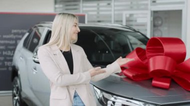 Gösteri salonu deneyimi, potansiyel alıcılar için geniş yaylı yeni bir arabayı tanıtan bir kadını gösteriyor.