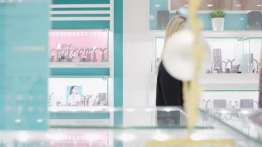 Kız, mükemmel hediyeyi düşünürken mağaza aynasında takılara hayran.