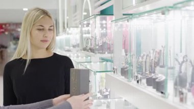 Kız mağazadaki mücevher seçimini beğenirken mükemmel hediyeyi düşünüyor.