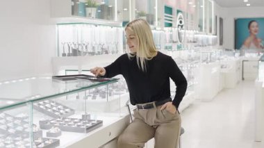 Yavaş çekimde anlamlı bir hediyeyi düşünürken bir mağazadaki mücevherlere hayran olan kız.