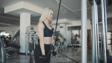 Odaklanmış kız, modern spor salonunda yavaş çekimde kablo çalışması yapıyor.