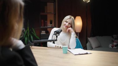 Nişanlı kadın, mikrofon kurulumlu rahat bir stüdyoda iş podcast 'i sunuyor.