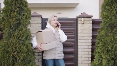 Banliyö mahallesindeki bir eve paket teslimatı yapan bir kadın telefon görüşmesi yapıyor.