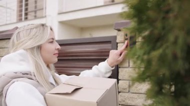 Bir kadın paketini teslim ediyor ve sessiz bir mahalledeki bir konutta kapı zili çalıyor.