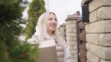 Teslimatçı kadın gün içinde eve bir paket getiriyor.