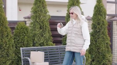 Kadın, güneşli bir günde teslimat kutusunu yönetirken eve paket getiriyor.