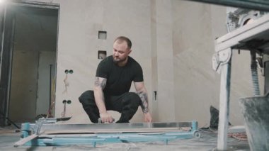 Tadilat sırasında inşaat alanında büyük bir fayans kaldıran bir adamın yavaş hareketi.