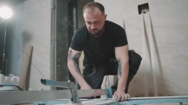 Adam ağır çekimde modern bir inşaat alanında fayans döşeme üzerinde çalışıyor.