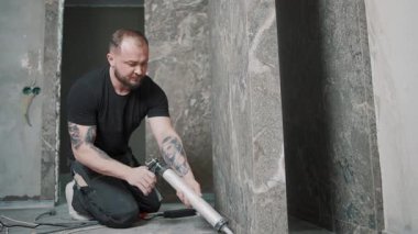 Modern evdeki yenileme projesi sırasında yavaş çekimde kiremitlere dolgu macunu süren adam.