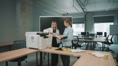 İş dünyasından profesyoneller, belge ve yazıcı kullanırken bir yandan da projeyi tartışan bir ofis alanında işbirliği yaparlar.