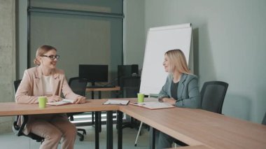 İş adamları, modern ofis ortamında dokümanların yer aldığı bir proje hakkında toplantı yapıyorlar.