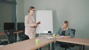 Modern ofiste kadın sunucu ve kadın yavaş çekimde notlar alırken iş toplantısı.
