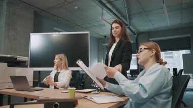 İş dünyası, ofis ortamında işbirliği içinde evrak ve fikirleri ağır çekimde tartışıyor.